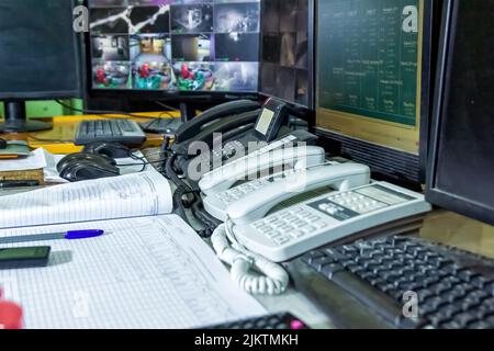 Nahaufnahme mehrerer Telefone und Computer auf einem Schreibtisch mit einem Notebook davor Stockfoto