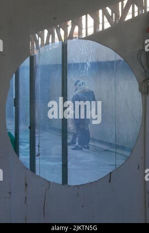 Ein Blick auf zwei Männer, die durch ein rundes Fenster in der Holzwand rauchten Stockfoto