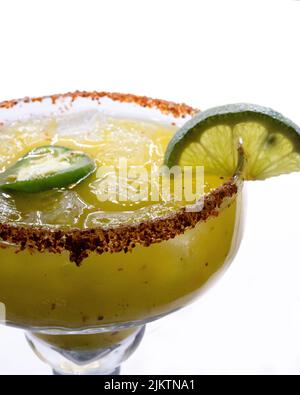 Eine selektive Fokusaufnahme eines grünen margarita-Getränks mit Limette und Jalapeno auf weißem Hintergrund Stockfoto