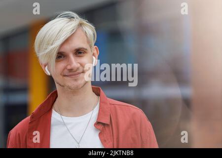 Schönes Männerportrait. Junge Hipster Person mit weißen Haaren und Ohrhörern. Stockfoto