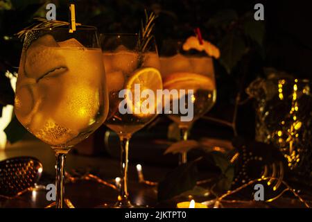 Die drei verschiedenen Gin Tonic Cocktails in Weinglas, gemütlicher weicher Hintergrund mit Pflanzen und Barausstattung Stockfoto