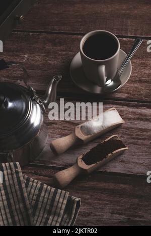 Zenitale Ansicht einer Kaffeetasse mit Milchkännchen und Holzlöffeln auf einem Holztisch mit Textraum Stockfoto