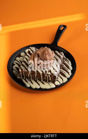 Eine vertikale Aufnahme eines Brownie mit geschmolzener dunkler und weißer Schokolade und einem Eis auf der Oberseite Stockfoto
