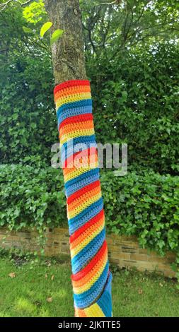 Eine vertikale Aufnahme eines Baumstamms mit gestricktem bunten Cover Stockfoto