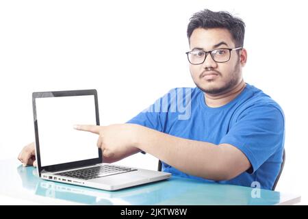 Junger Mann mit leerem weißen Laptop-Bildschirm und Zeigefinger Stockfoto