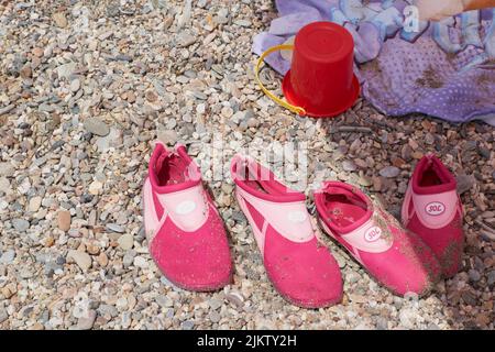 Hausschuhe neben einem Eimer und Handtuch auf dem Sand am Strand, Vera, Spanien Stockfoto