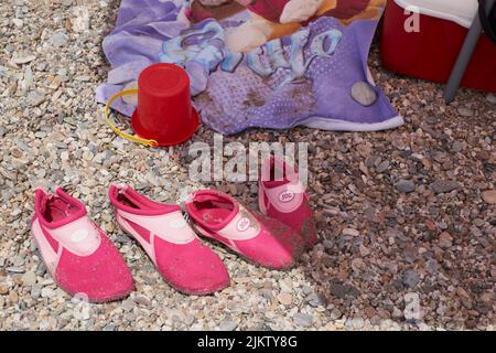 Hausschuhe neben einem Eimer und Handtuch auf dem Sand am Strand, Vera, Spanien Stockfoto