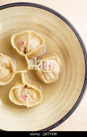 Eine vertikale Draufsicht auf Dampfknödel in einer Schüssel auf einem weißen Tisch Stockfoto