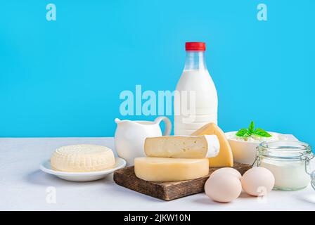 Milchprodukte und Eier auf blauem Hintergrund. Verschiedene Käsesorten, Milch, Rahm und Eier auf blauem Hintergrund. Stockfoto