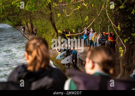 Surfer in München am Eisbach warten darauf, ins Wasser zu springen. Beliebtes Ziel, werden die Surfer von vielen Menschen beobachtet. Stockfoto