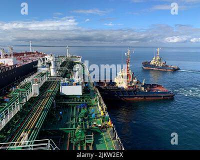 Schlepper, die an einem sonnigen Tag während des Schiffsbetriebs einem Schiff helfen Stockfoto