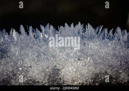 Eine Nahaufnahme von Schneekristallen auf dunklem Hintergrund Stockfoto