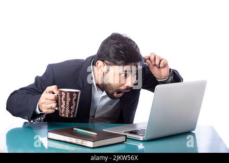 Überrascht oder erstaunt Geschäftsmann Blick auf Laptop, während Kaffee trinken in isolierten Hintergrund Stockfoto