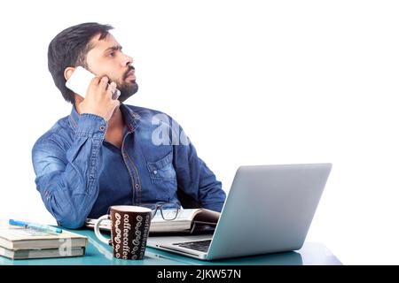Ein Mann, der auf dem Handy sprach, lenkte von der Arbeit am Laptop ab Stockfoto