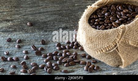 Ein Sackleinen gefüllt mit Kaffeebohnen und viele verschüttete vor. Stockfoto