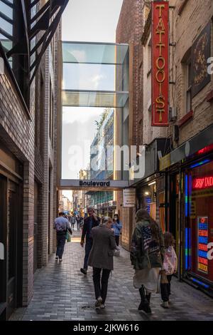 Eine vertikale Aufnahme von Menschen, die in einer kleinen Gasse in London, Großbritannien, spazieren gehen Stockfoto