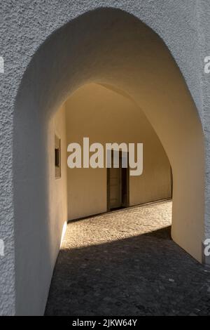 Eine vertikale Aufnahme eines weißen Steinbogens mit Sonnenstrahlen am Ende in St. Gallen, Schweiz Stockfoto