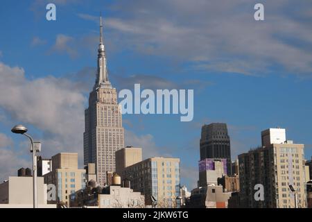 Das Empire State Building und die New Yorker modernen Gebäude unter dem blau bewölkten Himmel Stockfoto