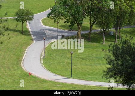 Ein schöner Blick auf den Bela Vista Park in Lissabon, Portugal mit hellgrünem Gras und Bäumen um Gehwege an einem sonnigen Tag Stockfoto