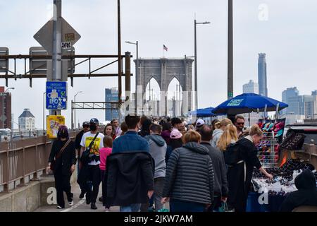 Touristen kommen wieder nach New York City. Am 13. April 2022 läuft eine große Menschenmenge über die Brooklyn Bridge in New York City. Stockfoto