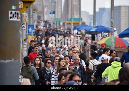 Touristen kommen wieder nach New York City. Am 13. April 2022 läuft eine große Menschenmenge über die Brooklyn Bridge in New York City. Stockfoto