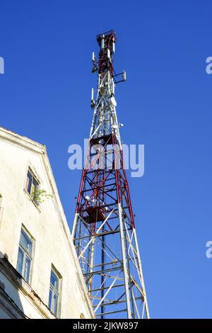 Hoher moderner Telekommunikationsturm in der Stadt mit TV-Antennen und Satellitenschüsseln auf klarem blauen Himmel Hintergrund Stockfoto