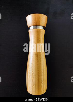 Eine braune Salz-Pfeffermühle aus Holz, isoliert auf schwarzem Hintergrund Stockfoto