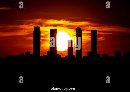 Madrid, Spanien. März 2021. Sonnenuntergang über der Silhouette der fünf Türme des nördlichen castellana von Madrid und die Sonne im Hintergrund zwischen ihnen Stockfoto