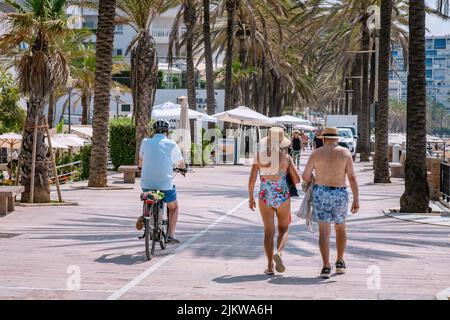 Zwei ältere Menschen gehen auf einer Fußgängerstraße entlang der Küste von Marbella. MARBELLA, MALAGA/SPANIEN - JULI 21 2022 Stockfoto