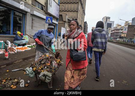 Fußgänger kommen an Straßenhändlern vorbei, die ihre Produkte auf den Straßen des zentralen Geschäftsviertels von Nairobi in Kenia verkaufen. Die meisten kenianischen Schulen waren auf Augus Stockfoto