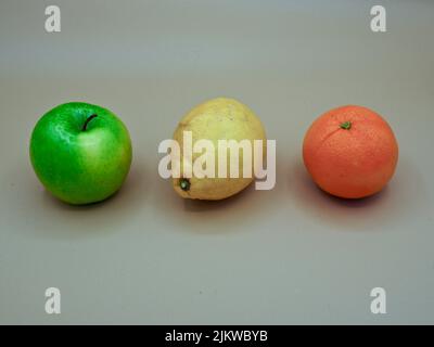 Trio von bunten Früchten, orizontal auf einem neutralen hellen Hintergrund dargestellt Stockfoto