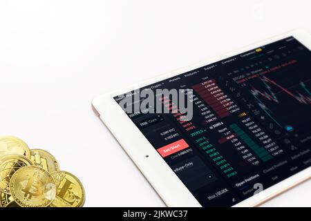 Ein Bildschirm mit Bitcoin Trading Forex Graph und vielen goldenen Bicoin Münzen isoliert auf weißem Hintergrund Stockfoto