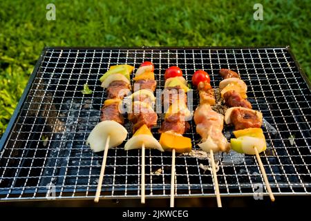 Eine Nahaufnahme der Spieße mit Fleisch und Gemüse, die auf einem Grill braten Stockfoto