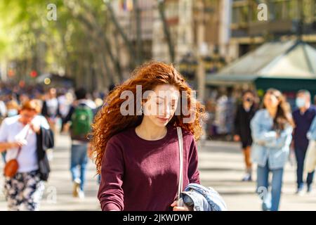 BARCELONA, SPANIEN - 8. APRIL 2022: Menschen, die entlang der Ramblas in Barcelona (Spanien), der berühmtesten Straße der Stadt, spazieren gehen. Stockfoto