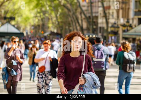 BARCELONA, SPANIEN - 8. APRIL 2022: Menschen, die entlang der Ramblas in Barcelona (Spanien), der berühmtesten Straße der Stadt, spazieren gehen. Stockfoto