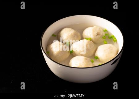 Eine Nahaufnahme von sechs hausgemachten Fleischbällchen auf der weißen Platte isoliert auf dem schwarzen Hintergrund Stockfoto