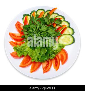 Tomaten, Gurken, Paprika in Scheiben geschnitten und mit Petersilie und Salat garniert. Teller Mit Frischem Gemüse. Isolieren. Stockfoto