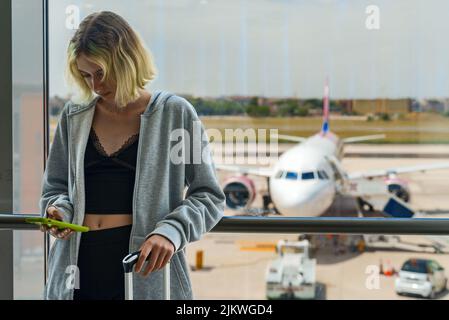 Das Teenager-Mädchen wartet auf ihren Flug am Flughafen. Stockfoto