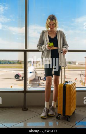 Das Teenager-Mädchen wartet auf ihren Flug am Flughafen. Stockfoto