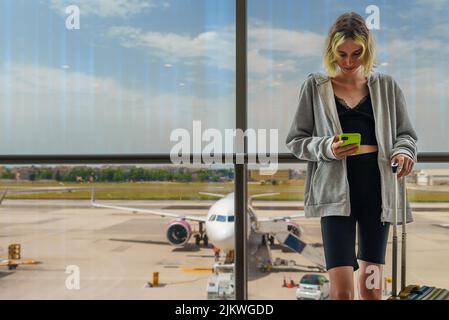 Das Teenager-Mädchen wartet auf ihren Flug am Flughafen. Stockfoto