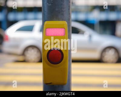 Nahaufnahme einer Signaltaste für den Fußgängerüberweg, die an einer Fußgängerüberfahrt aufgenommen wurde. Eine Ruftaste, die das Licht durchlässt. Stockfoto