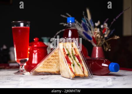 Sandwich mit Füllung in einer Plastikverpackung und einem Getränk in einer Flasche. Stockfoto