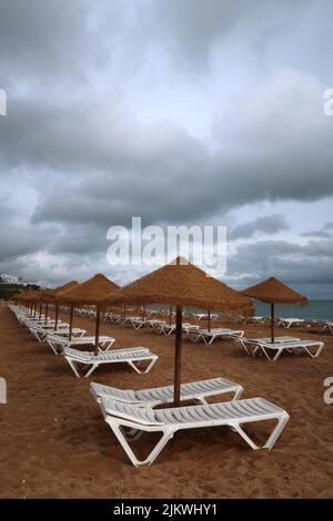 Eine Reihe von Strandliegen an einem leeren Strandresort in Südeuropa an einem bewölkten Tag ohne Touristen. Stockfoto