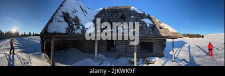 Eine Nahaufnahme eines alten Holzhauses auf einem Hügel im Winter mit Schnee bedeckt an einem sonnigen Tag Stockfoto