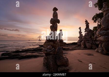 Die großen und kleinen Steine stapelten sich bei Sonnenuntergang am Sandstrand übereinander Stockfoto