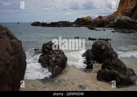 Im Sommer schwammen schäumende Wellen ruhig am Sandstrand Stockfoto