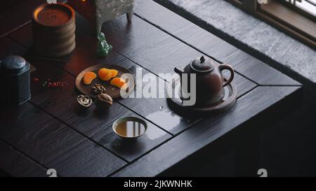 Eine Aufnahme einer Teekannen mit einer Tasse Tee auf einem Holztisch Stockfoto