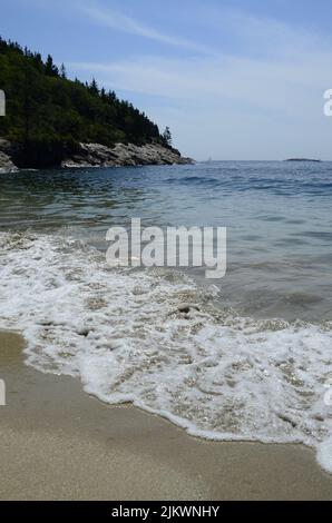 Im Sommer schwammen schäumende Wellen ruhig am Sandstrand Stockfoto