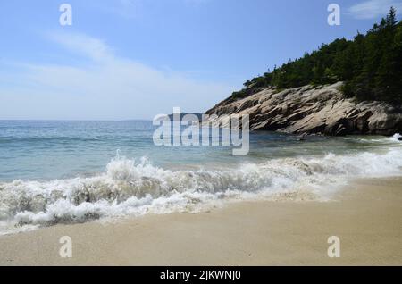 Im Sommer schwammen schäumende Wellen ruhig am Sandstrand Stockfoto