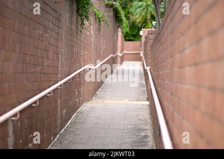 Eine schräge Gasse zwischen Ziegelmauern mit Geländern in einem Park in Hongkong Stockfoto